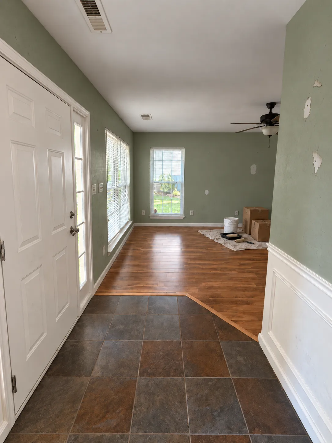 Before: an entryway with sage-colored walls, peeling paint, and painting supplies on a drop cloth.